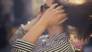 A woman with both hands in her hair at the roots