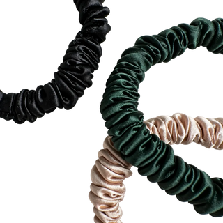 Three satin hair scrunchies in black, green, and beige on a white background