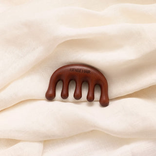 Brown hair gua sha on a beige fabric background
