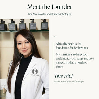 Founder Tina Mui, master stylist and trichologist, in a white AWARE coat in front of salon shelves
